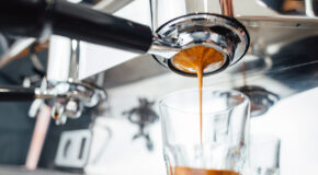 Nybrygget espresso renner ut av et portafilter og oppi et glass
