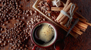 En kopp kaffe står på et bord sammen med mange forskjellige typer krydder