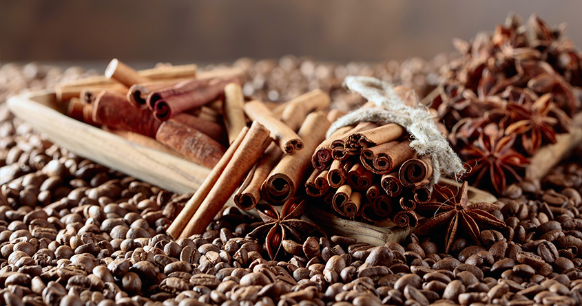 Mange forskjellige typer krydder ligger på en seng av kaffebønner