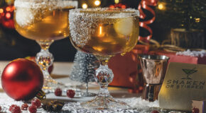 To glass med drinken The Cold Fashioned står på et bord med julepynt