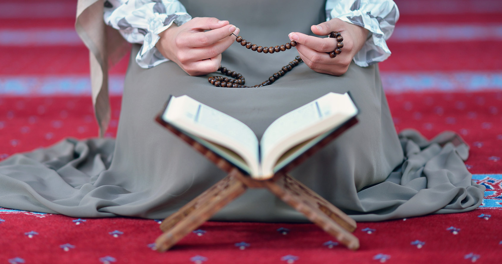En muslimsk kvinne sitter på et teppe og ber