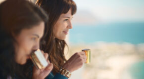To kvinner sitter ved siden av hverandre og drikker Evergood-kaffe fra gullkopper