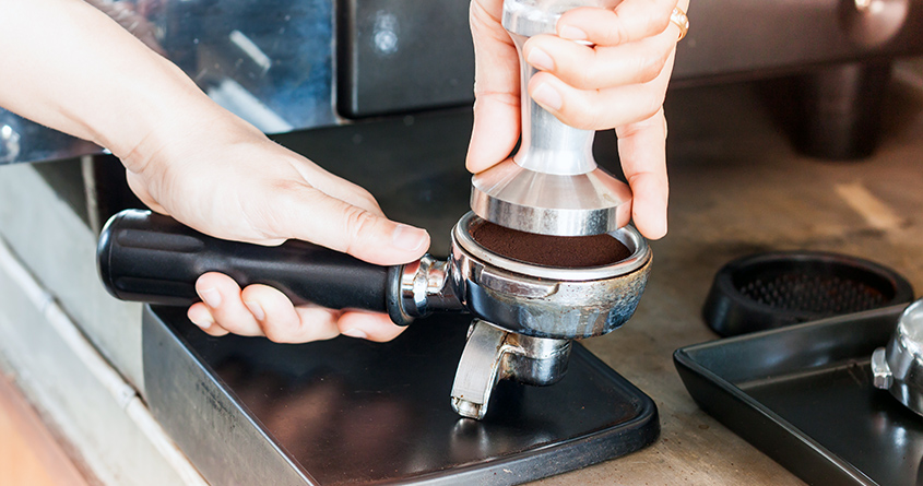 En barista tamper et portafilter for å lage espresso