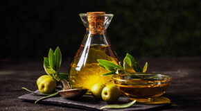 En glassmugge med olivenolje står på et bord