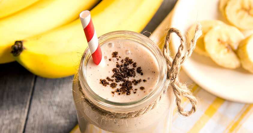 En banankaffe står på et bord ved siden av noen bananer