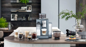 En gråblå Rivelia-kaffemaskin fra De’Longhi står på en kjøkkenbenk