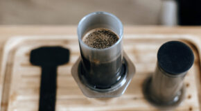 Kaffe brygges i en AeroPress som står på en trefjøl