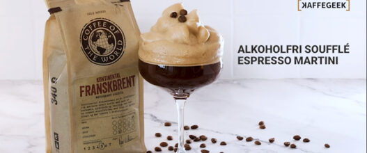 Et glass med alkoholfri soufflé espresso martini står ved siden av en pose med kaffe