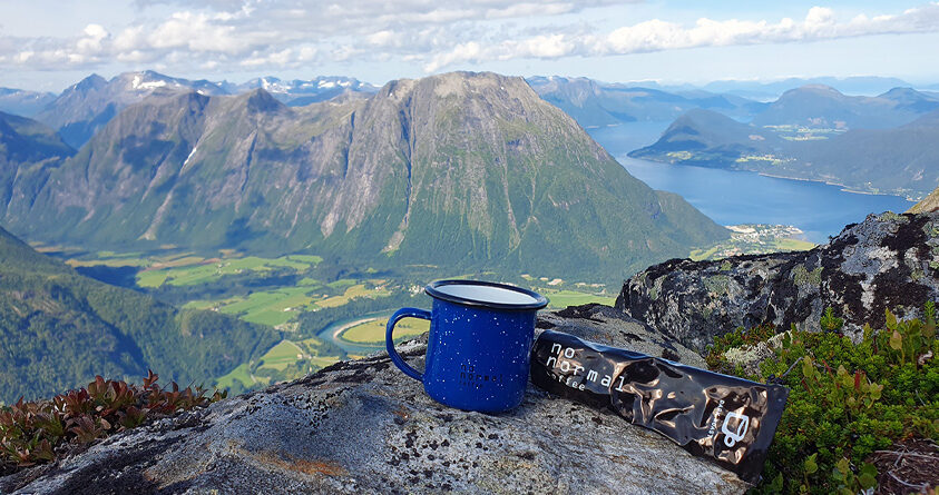 En tube med No Normal-kaffepasta ligger ved siden av en emaljekopp på toppen av Romsdalseggen