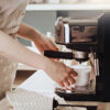 En kvinne lager espresso på en espressomaskin i hjemmet sitt