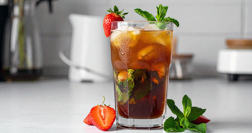 Et glass med alkoholfri jordbærmojito står på en lys kjøkkenbenk