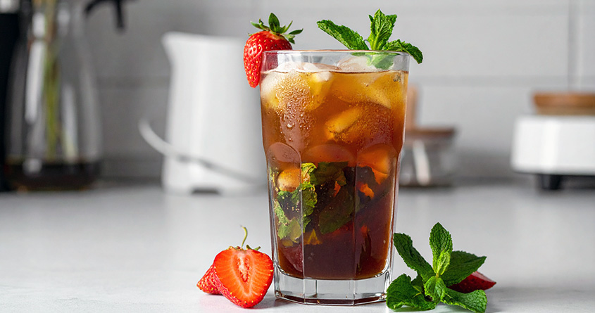 Et glass med alkoholfri jordbærmojito står på en lys kjøkkenbenk
