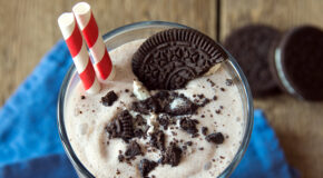Et glass med Oreo-iskaffe står på en blå duk