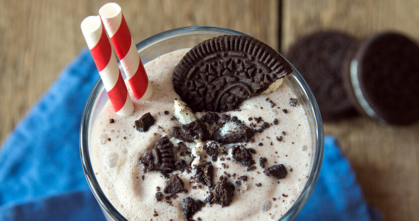 Et glass med Oreo-iskaffe står på en blå duk