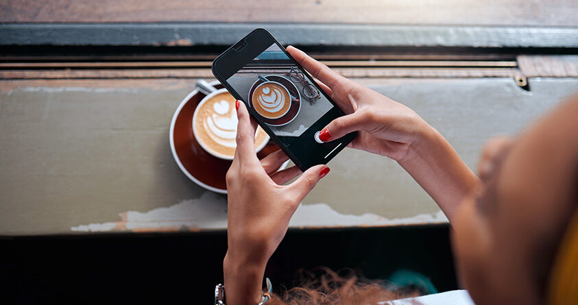 En person tar et bilde av en kaffe latte med lattekunst