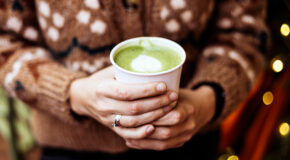En kvinne en kopp med matcha latte