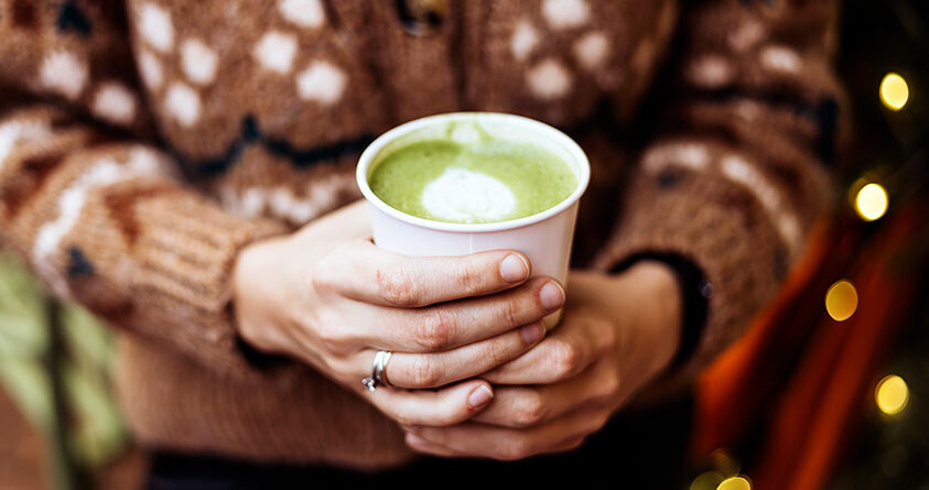 En kvinne en kopp med matcha latte
