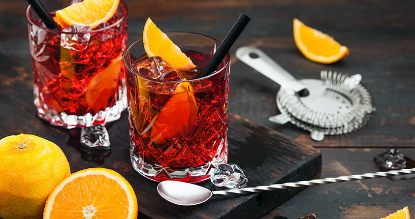 To glass med espresso negroni står på en mørk trefjøl