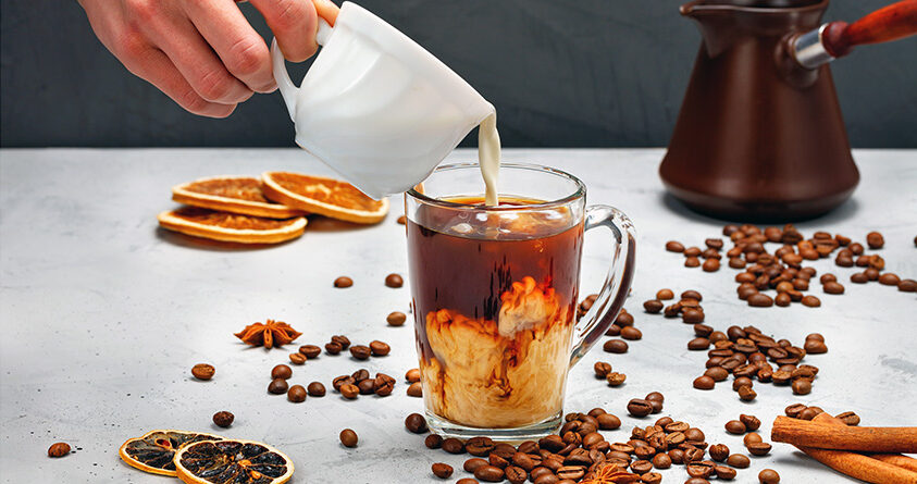 En person heller melk oppi en krydderkaffe