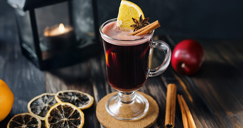 Et glass med toddy med eple og kaffe står på en kjøkkenbenk