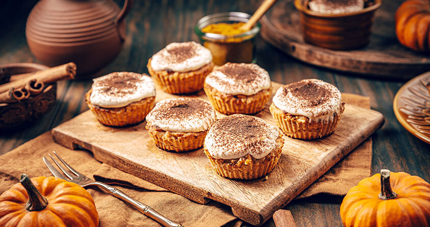 Seks gresskarmuffins med kaffe ligger på en fjøl