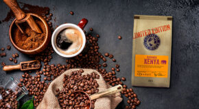 En pose med Karinga ligger ved siden av en kopp kaffe og kaffebønner