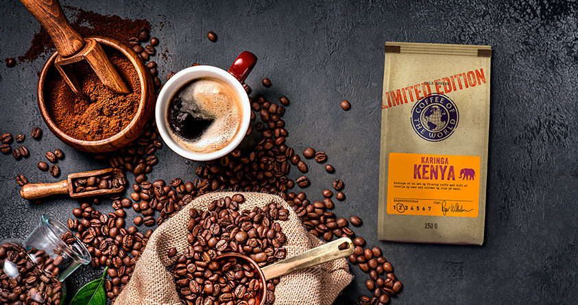 En pose med Karinga ligger ved siden av en kopp kaffe og kaffebønner