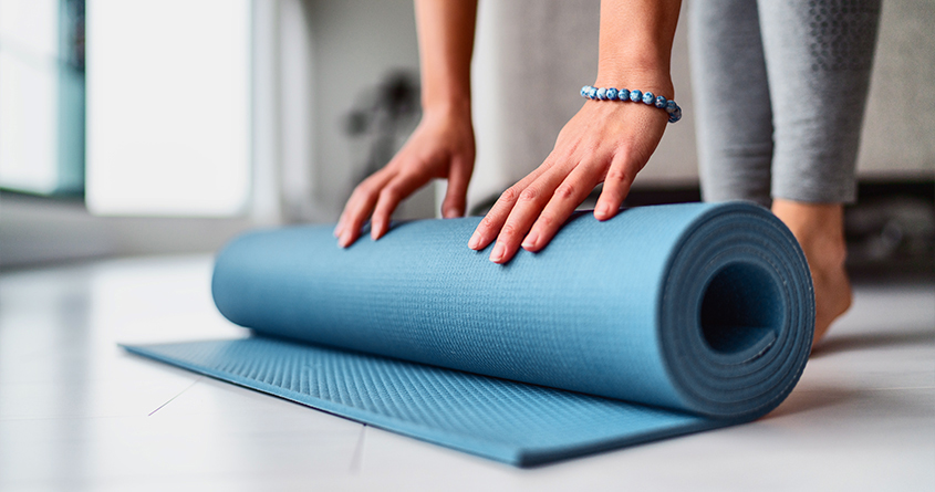 En person ruller ut en yogamatte for å begynne en treningsøkt