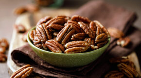 En skål med ristede pekannøtter står på et kjøkkenhåndkle