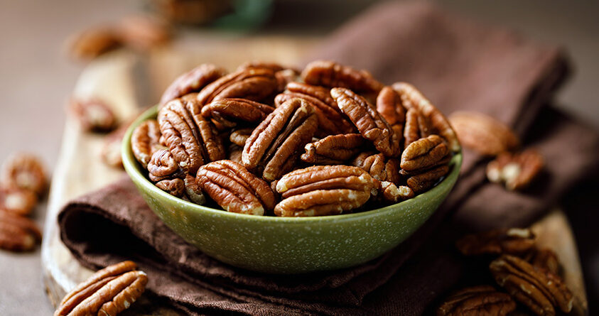 En skål med ristede pekannøtter står på et kjøkkenhåndkle