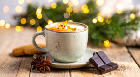 En kopp med kaffe mocca står på en benk foran julepynt