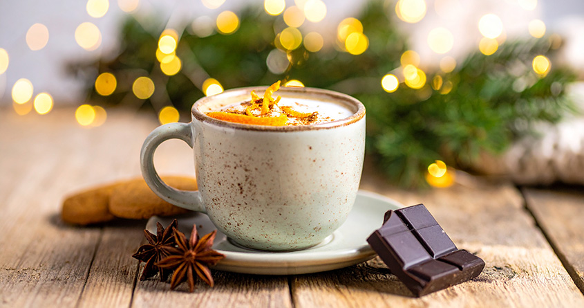 En kopp med kaffe mocca står på en benk foran julepynt