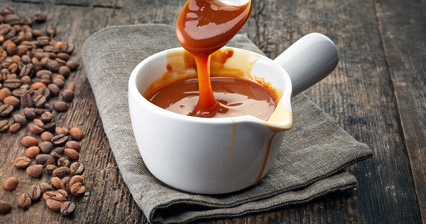 En skje rører oppi en beholder med kaffekaramellsaus