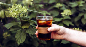 En person holder et glass med kaldbrygget kaffe