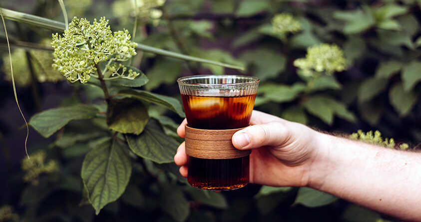 En person holder et glass med kaldbrygget kaffe