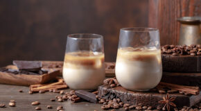 To stilige glass med kaldbrygget kaffe står ved siden av hverandre på et rustikt trebord