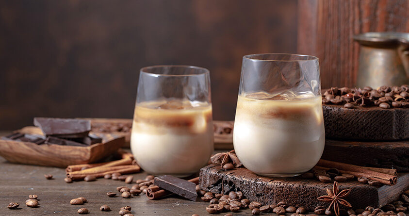 To stilige glass med kaldbrygget kaffe står ved siden av hverandre på et rustikt trebord