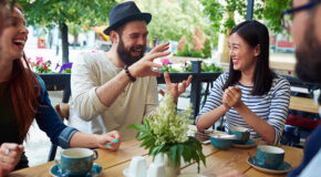En vennegjeng sitter på kafé og snakker sammen og ler
