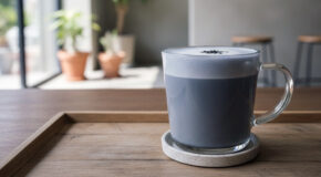 En kopp med svart sesamlatte står på et serveringsbrett av tre