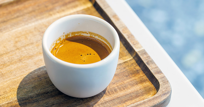 En cafezinho står på et trebrett