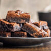 Et fat med brownies står foran en mokkakanne og en kaffekopp