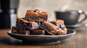 Et fat med brownies står foran en mokkakanne og en kaffekopp