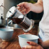 En mann heller kaffe fra en presskanne oppi to kopper