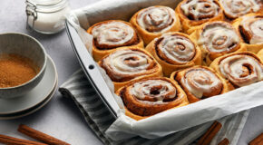 Et brett med kanelboller er dekket med kaffeglasur