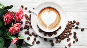 En kopp kaffe med lattekunst i form av et hjerte står på et bord