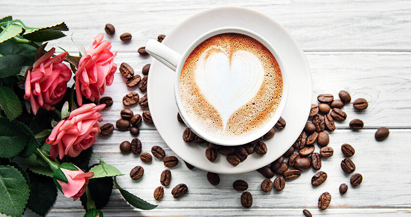 En kopp kaffe med lattekunst i form av et hjerte står på et bord