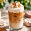 Et glass med islatte med marshmallowskum står på en kjøkkenbenk