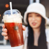 En ung person fra Gen Z holder frem en iskaffe med krem og bær