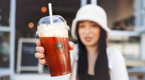 En ung person fra Gen Z holder frem en iskaffe med krem og bær