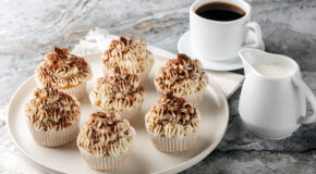 Tiramisu-muffins står på en hvit asjett ved siden av kaffekopp og en mugge med melk
